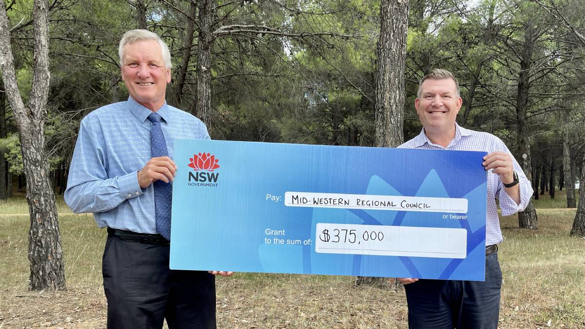 PARTNERSHIP: Mid-Western Regional Council general manager Brad Cam with Member for the Dubbo electorate Dugald Saunders holding a giant cheque at Flirtation Hill. Picture: SUPPLIED