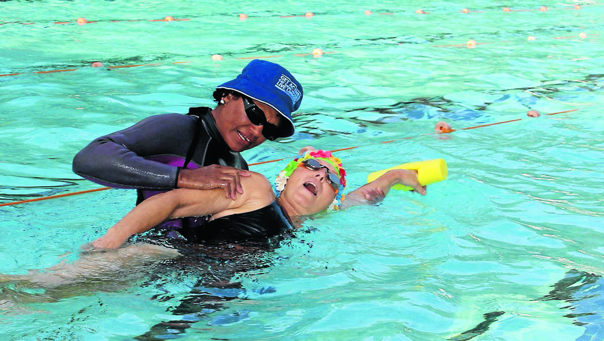 Swimming instructor Lavenia Whippy helps Sheryl Campbell practice her breathing during a learn to swim class at the Mudgee Pool.	150213/lsadultswim/001